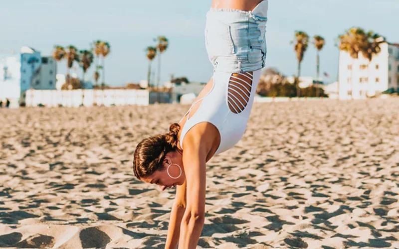 a girl doing hand stand on beach